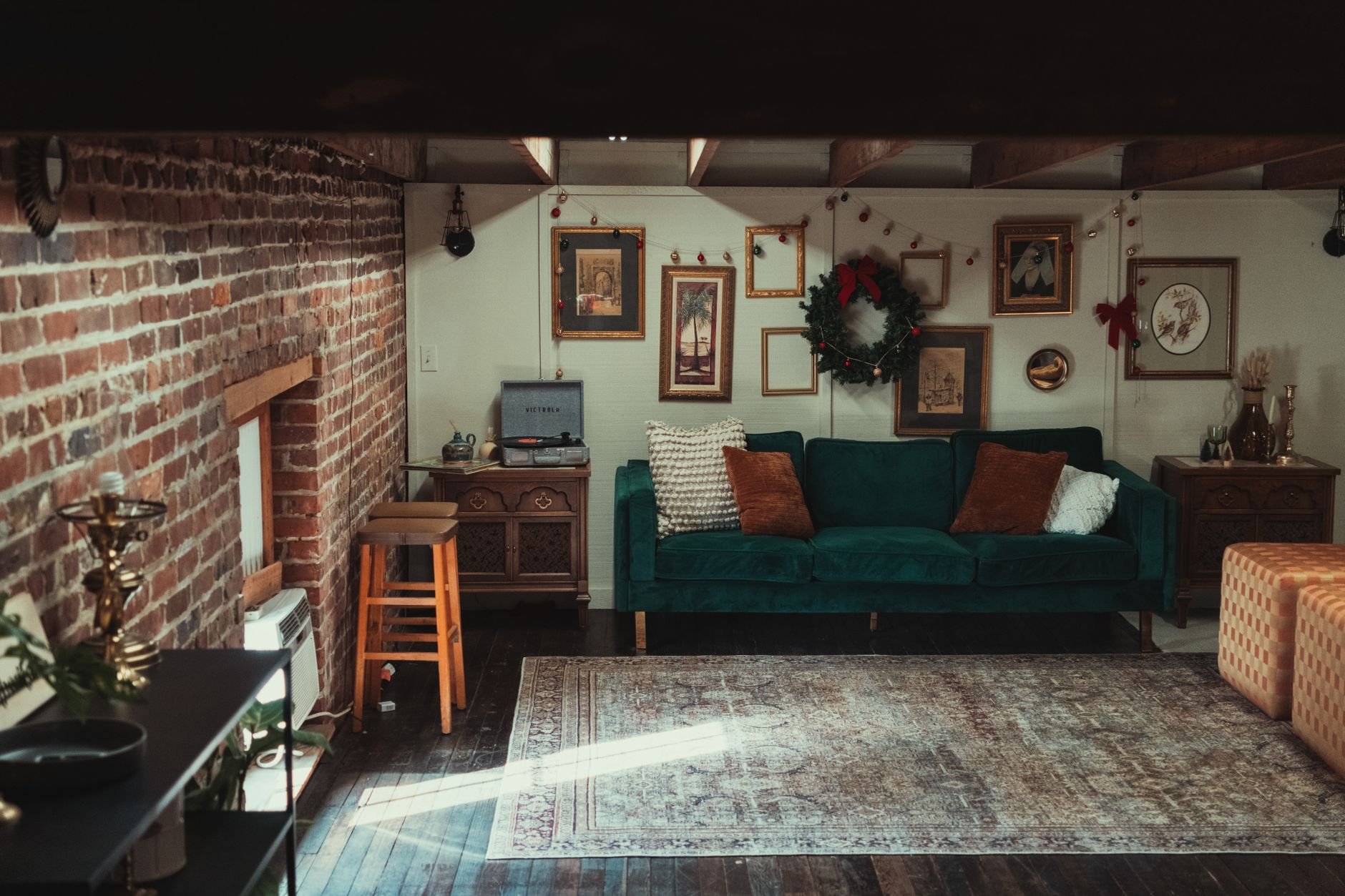 Warm and inviting living room featuring a vintage sofa, brick wall, and artwork display.